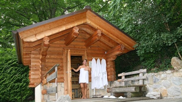 Une cabane en bois avec un mur en pierre et un escalier en bois menant à l’entrée.
