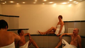 Un groupe de personnes se trouve dans un endroit qui ressemble à un spa, avec un mur carrelé et un banc.