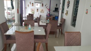 Un comedor con un separador de vidrio, sillas acolchadas, una mesa con una computadora portátil y diversas decoraciones en las paredes.