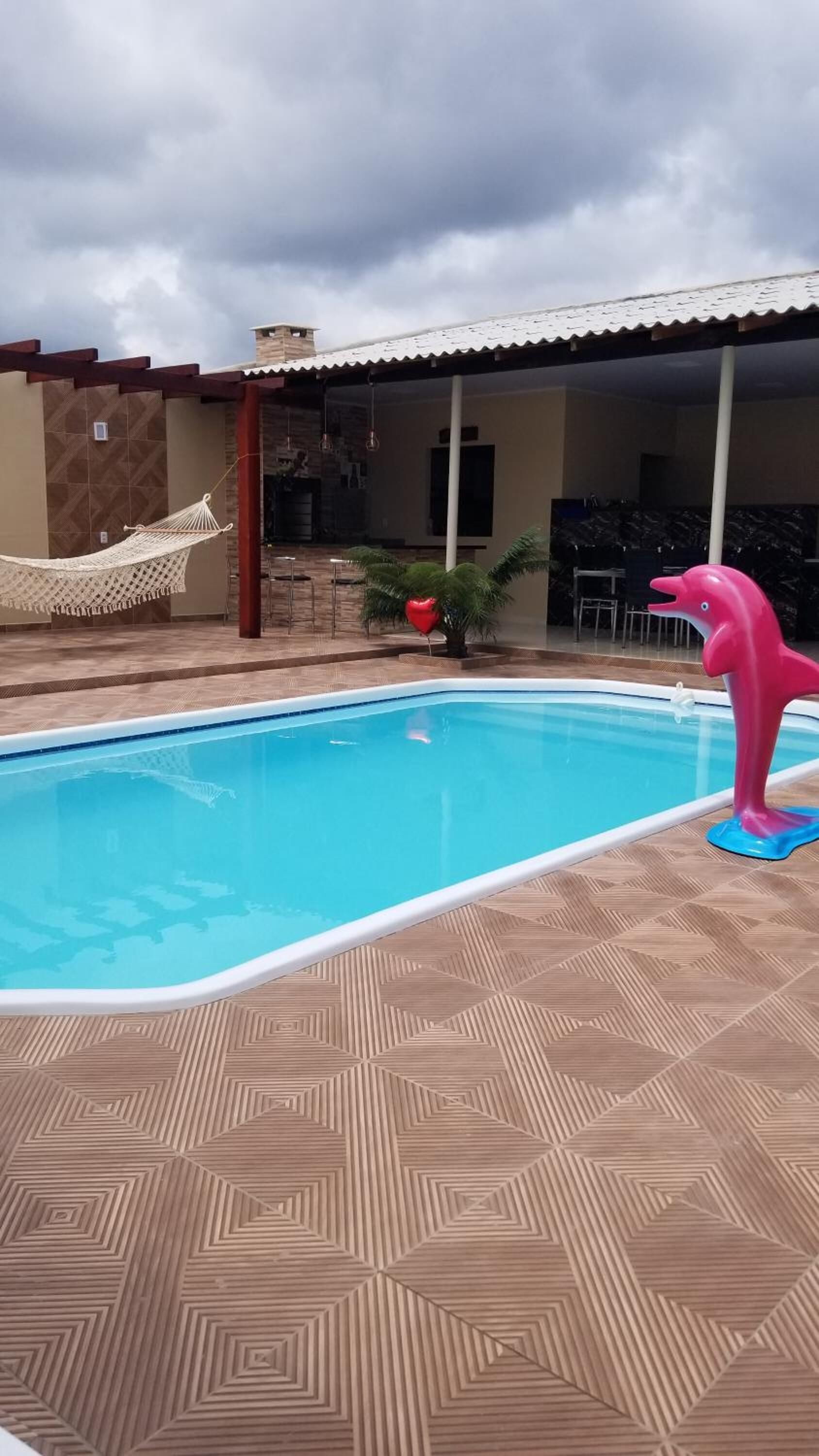 A swimming pool with a geometric patterned floor, a hammock, and a pink dolphin float.