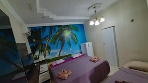 Un dormitorio con cama, cómoda, espejo, ventilador de techo y un mural en la pared con palmeras.