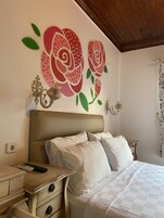 Un dormitorio con cama, mesitas de noche y un cuadro floral en la pared.