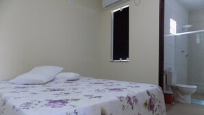 Un dormitorio con una cama, una ventana y un baño visible a través de una puerta abierta.