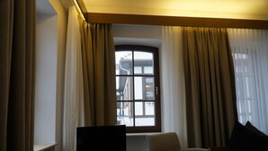 Een hotelkamer met een groot raam, een flatscreen televisie op een houten tafeltje en twee stoelen.