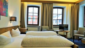 Een hotelkamer met twee bedden, een televisie, een bureau en een stoel.
