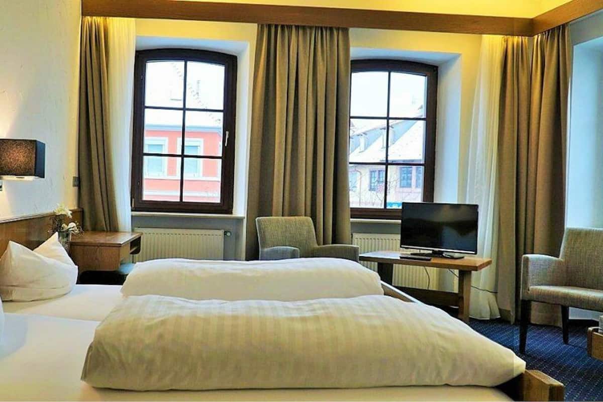 Habitación de hotel con dos camas, televisor, escritorio y una silla.