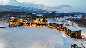 A snow-covered hotel with multiple buildings, a ski slope, and a mountainous backdrop. - Park Hyatt Niseko Hanazono (Kutchan)