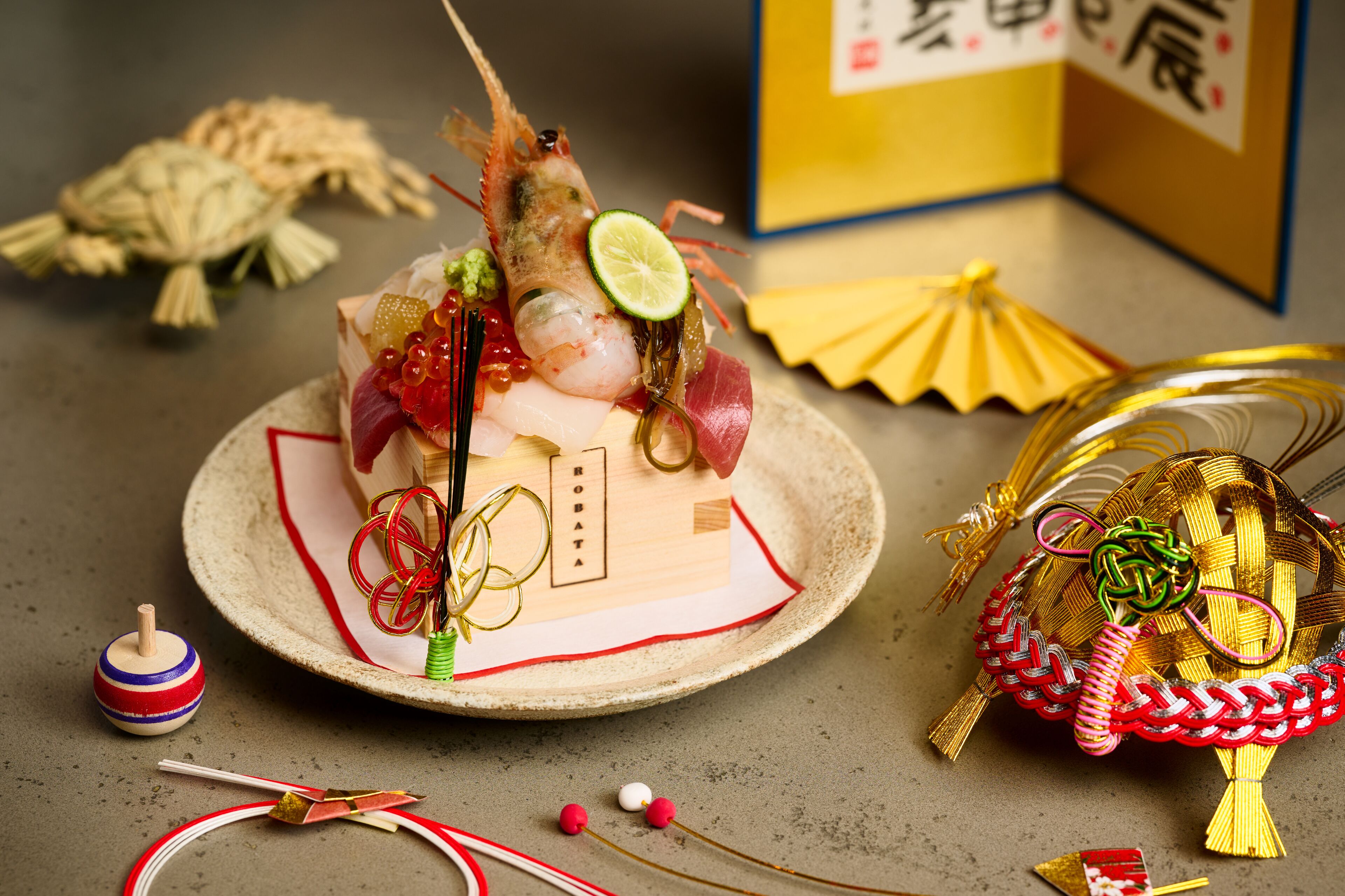 Um arranjo decorativo de alimentos em um prato, incluindo camarão, sashimi e outros enfeites.