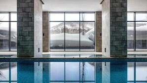 A pool with a view of snow-covered mountains through large windows. - Park Hyatt Niseko Hanazono (Kutchan)