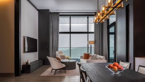 A modern living room with a dark wood dining table, two sofas, a TV, and a large window with a view of a mountain. - Park Hyatt Niseko Hanazono (Kutchan)