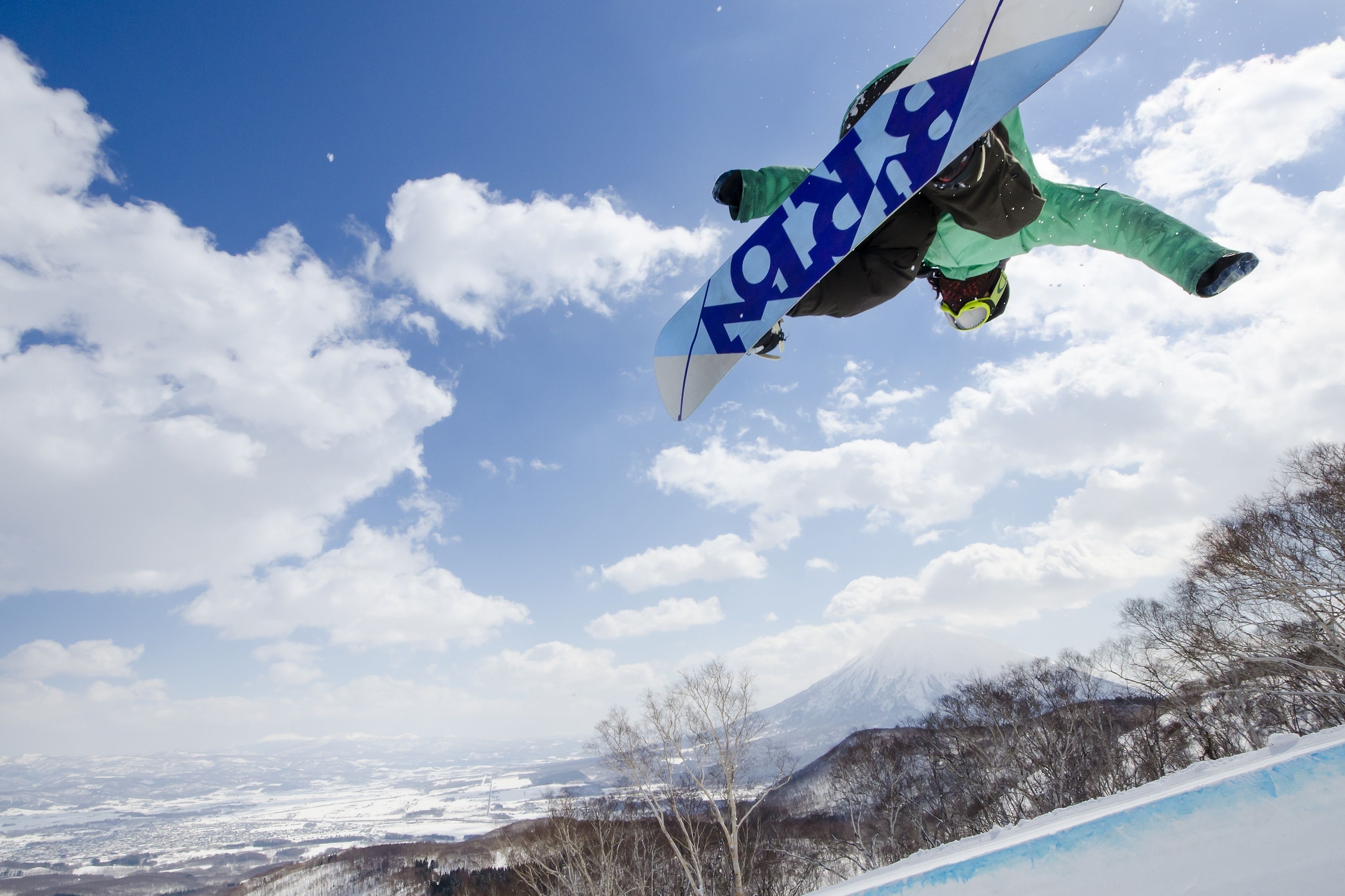 A snowboarder in mid-air against a clear sky.