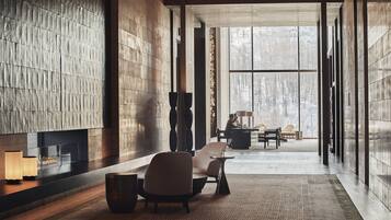 A modern interior with a fireplace, seating area, and large windows offering a view of a snowy landscape.