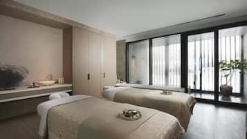 Een moderne hotelkamer met twee bedden, een groot raam, een wastafel en een plant.