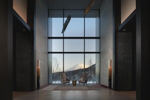 A modern interior with large windows, two armchairs, and a central table. - Park Hyatt Niseko Hanazono (Kutchan)