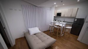 A compact room with a bed, a small kitchenette, and a dining area.