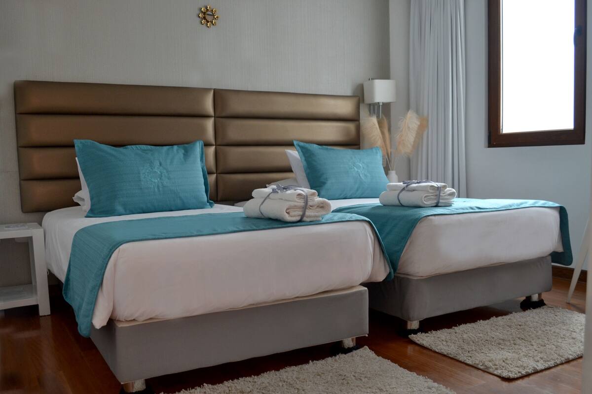 A double bed with a headboard, two pillows, and a folded towel.