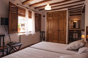 Une chambre avec un grand lit, une armoire en bois et une petite table avec une chaise.