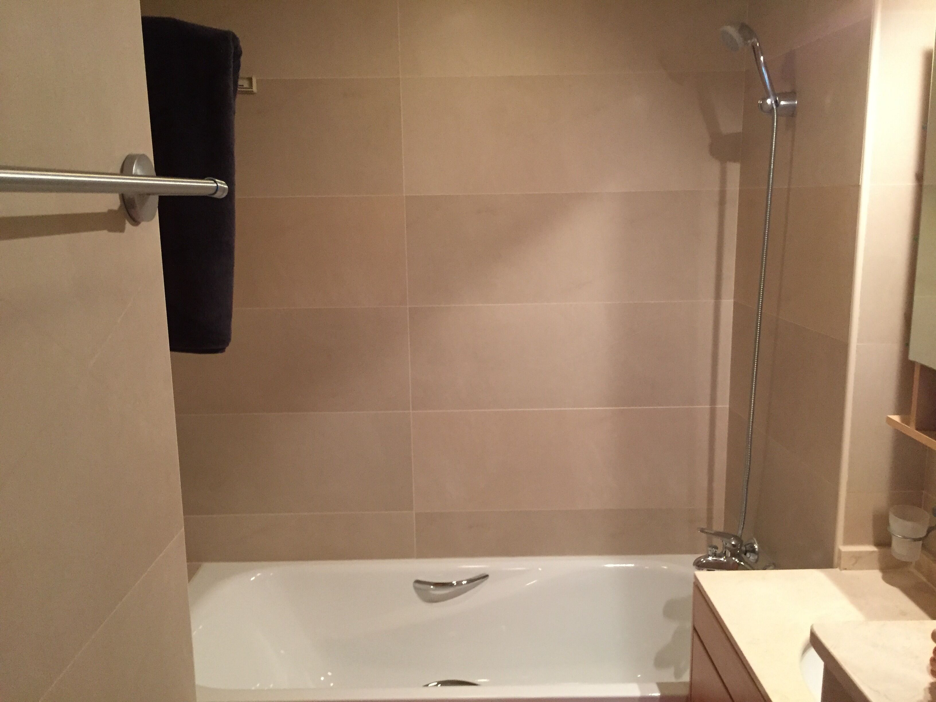 A modern bathroom with a bathtub, a shower, and a towel rack.