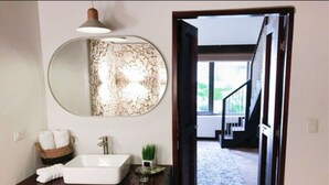 A bathroom with a large mirror, a white sink, and a dark wooden vanity. - Soy Local Insignia (Cartagena)