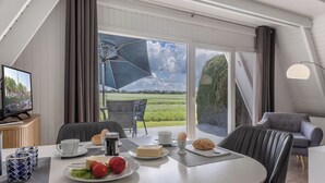 Een eethoek met een ontbijt gedekte tafel, met eieren, brood en tomaten.