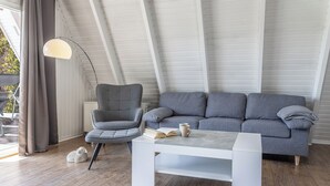 Een moderne woonkamer met een grijze bank, een witte salontafel en een hoge vloerlamp.