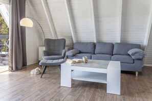 Un soggiorno moderno con un divano grigio, un tavolino bianco e una lampada da terra alta.