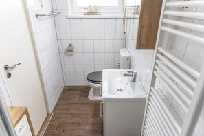 A small bathroom with a toilet, sink, and a window above the toilet.