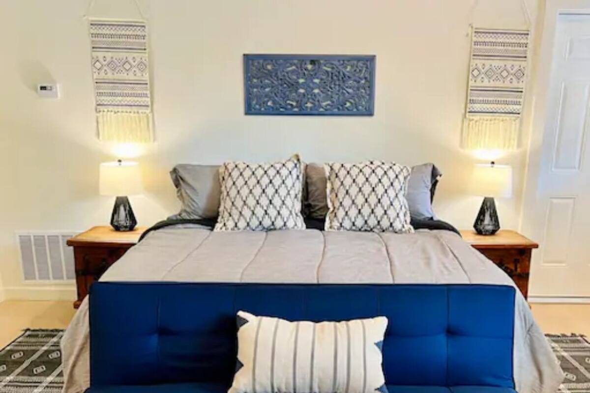 Un dormitorio con una cama, un sofá azul, dos mesitas de noche y adornos en la pared.