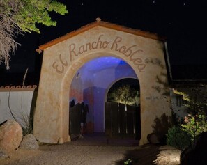 Une arche en pierre portant l’inscription « El Rancho Robles », de nuit.