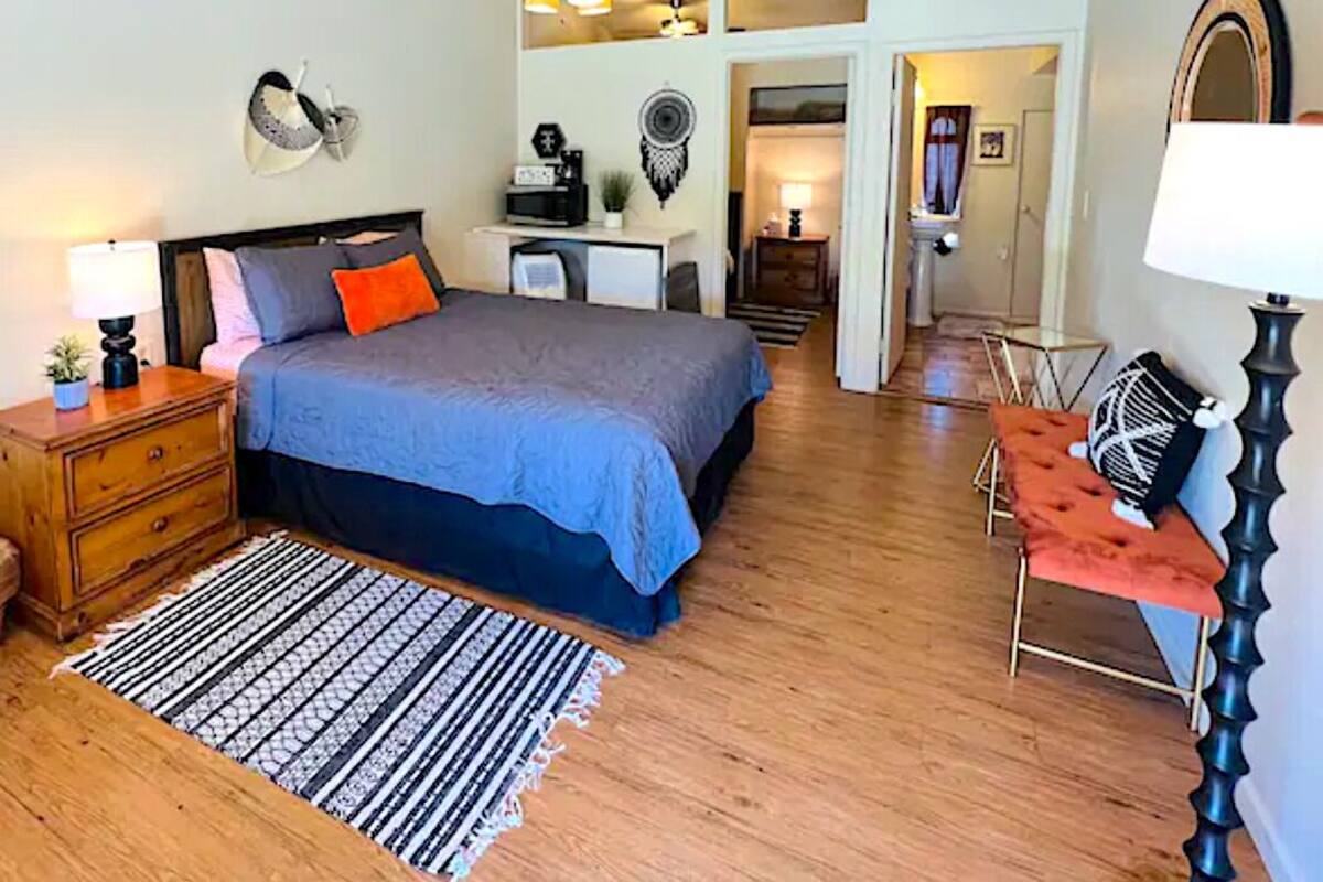 Un dormitorio con cama, mesita de noche, lámpara y escritorio con silla.
