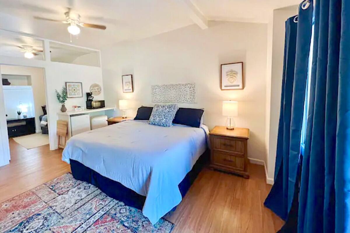 Un dormitorio con cama, mesitas de noche, escritorio y silla.