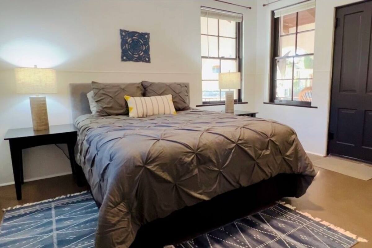 Un dormitorio con cama, dos lámparas de noche, una ventana y una puerta.