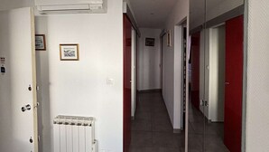 A hallway with a radiator, a white air conditioning unit, and red doors. - Bright apartment in Balaruc-les-Bains, pets allowed (Balaruc-les-Bains)