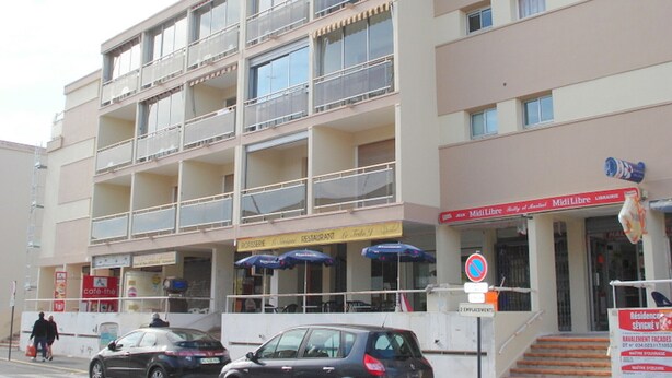 Un edificio de varios pisos con balcones, una cafetería y una fachada visible.