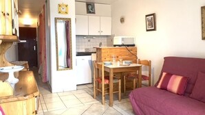 Un espacio habitable compacto con comedor, kitchenette y sofá.