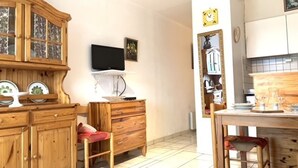 Un espacio habitable compacto con un mueble de madera, un televisor y una zona de cocina.