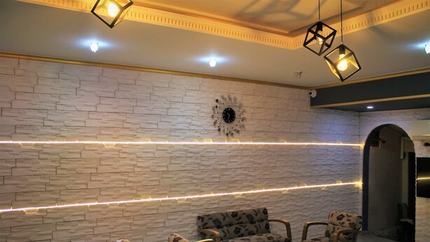 Un área de descanso moderna con pared de piedra, un reloj decorativo y una fila de sillas y una mesa.