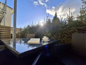 An outdoor dining area with a glass table, wicker chairs, a book, a cup, and a saucer. - Villa Waldstraße, Apartment 05 - Apartment 05 (Heringsdorf)