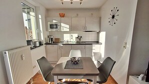 Een kleine keuken met een eettafel en stoelen, een magnetron en een spoelbak.