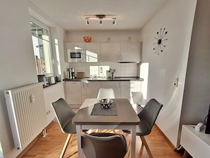 A compact kitchen with a dining table and chairs, a microwave, and a sink.