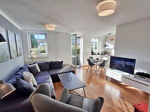A modern living room with a sofa, a dining table, and a TV. - Villa Waldstraße, Apartment 05 - Apartment 05 (Heringsdorf)