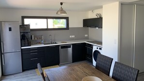 Eine moderne Küche mit Kühlschrank, Backofen, Geschirrspüler und einem Fenster über der Spüle.