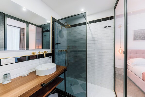 A modern bathroom with a glass-enclosed shower, a wooden vanity with a white sink, and a large mirror.