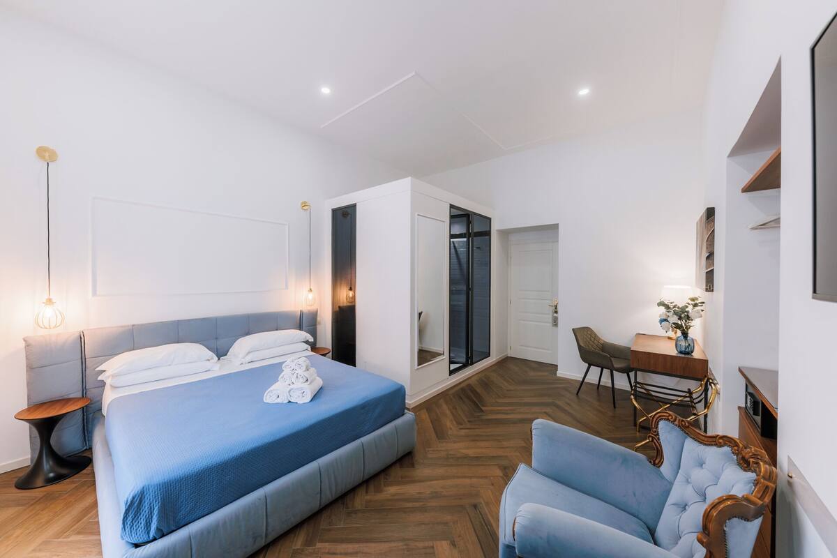 A modern bedroom with a large bed, a desk, and a chair.