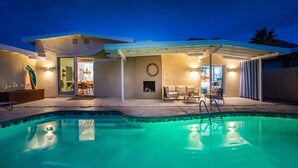 A modern house with a swimming pool, a patio with outdoor furniture, and a covered area with a fireplace. - The Exclusive Presidential House (La Quinta)