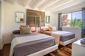 A bedroom with two beds, a ladder, a desk, and a large window with curtains.