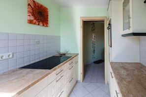 A kitchen with a light green wall, a black stove, and a decorative crown on the counter.