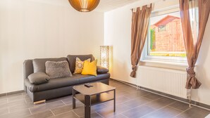 Ein modernes Wohnzimmer mit einem dunkelgrünen Ledersofa, einem kleinen Couchtisch und einer Pendelleuchte.