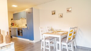 Eine moderne Küche mit blauen Schränken und einem Essbereich mit weißen Stühlen und einem Holztisch.