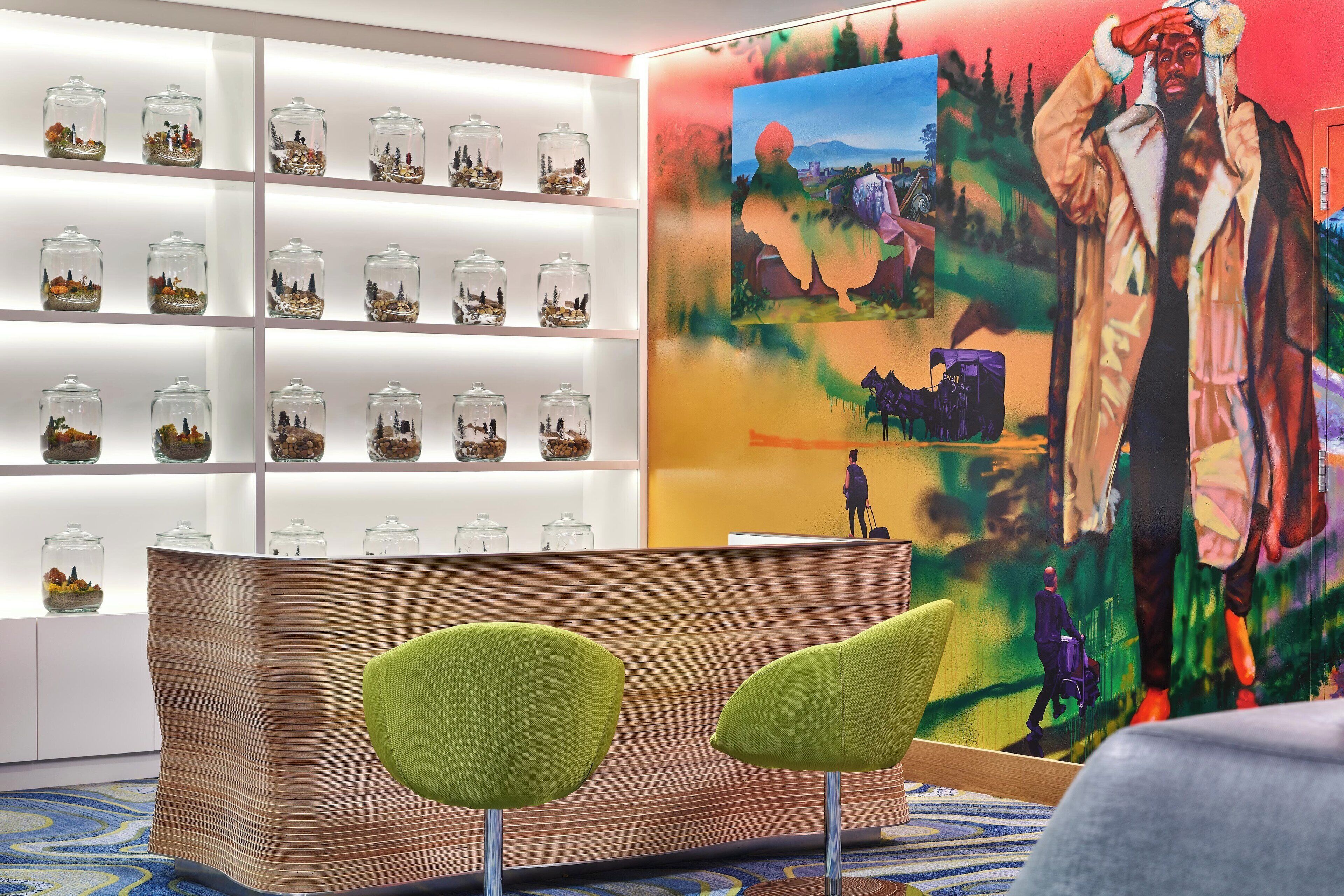 A reception area with a wooden reception desk, two green chairs, and a wall with glass jars containing miniature landscapes.